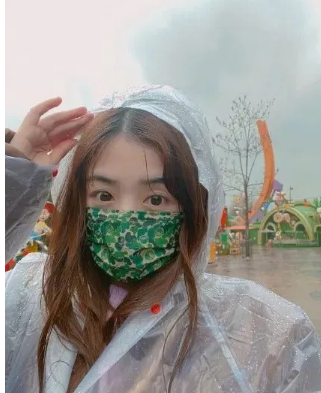 张含韵冒雨打卡迪士尼 穿雨衣戴花口罩头发淋湿